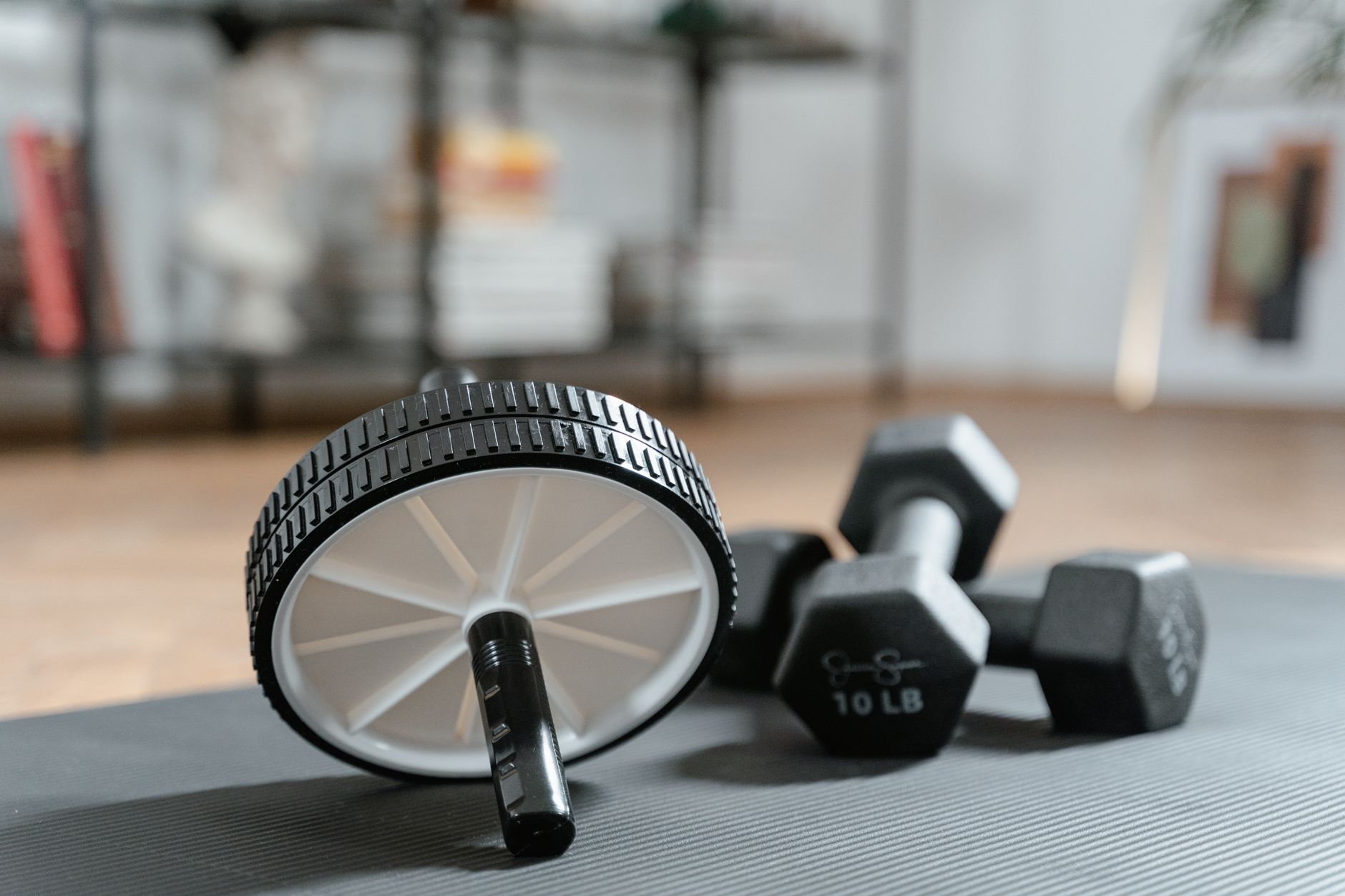 Ab roller and dumbbells on yoga mat, perfect for a home workout routine and healthy lifestyle. — Sporting & Fitness Injuries: