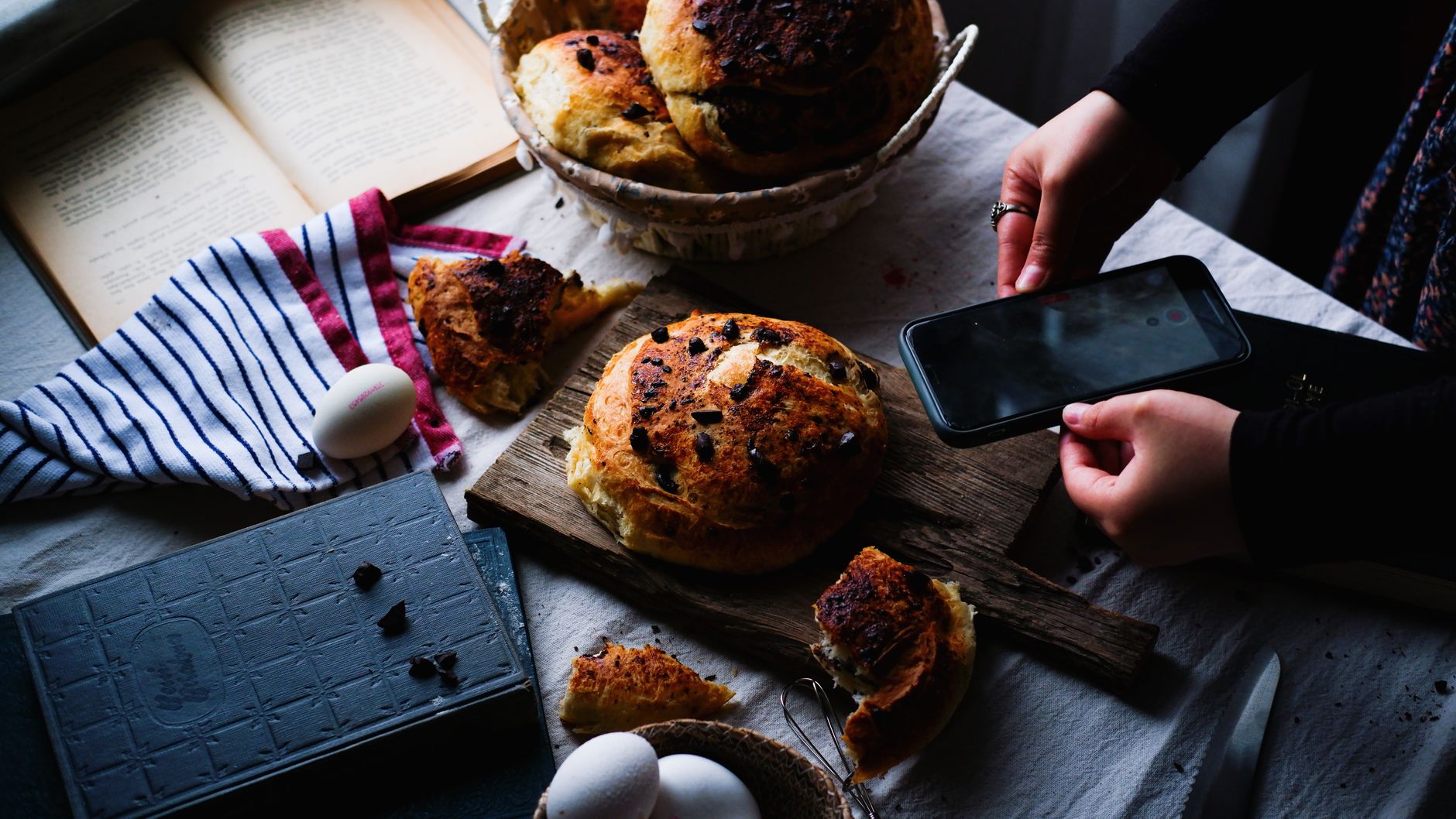 Artistic shot of homemade bread on a wooden board with a smartphone capture, embodying a rustic culinary scene. — Steak House