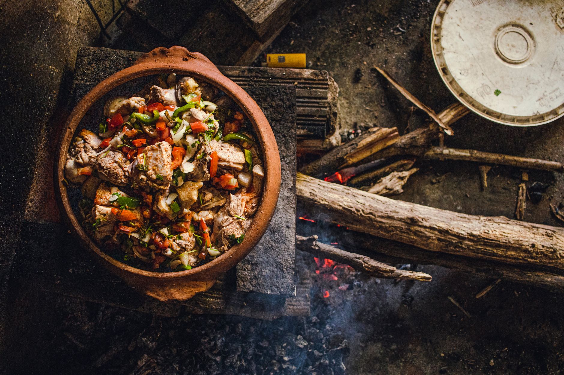 A rustic clay pot cooking meat and vegetables over an open wood fire in Brazil, showcasing traditional cuisine. — The Surpris